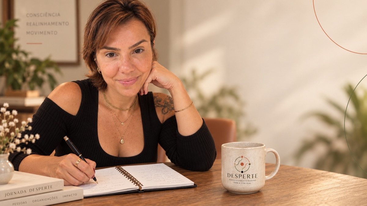 Marilu Cerqueira escrevendo num caderno, com a caneca da Desperte